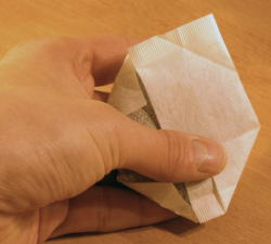 Die dritte Ecke hochgefaltet, die vierte noch offen. / The third corner folded up, the fourth still open.